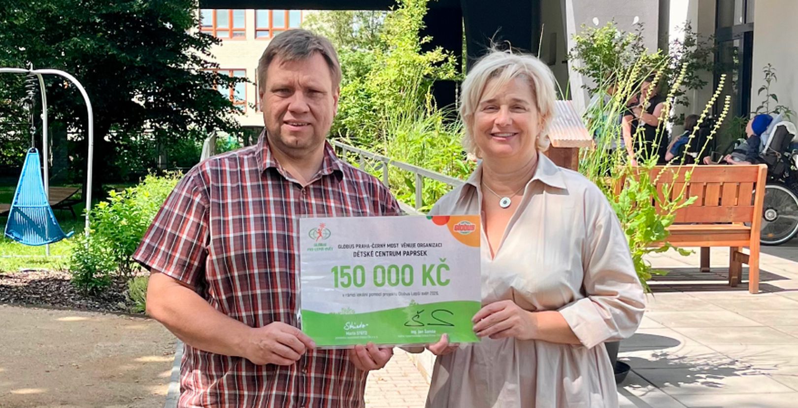 Muž a žena na terase s darovacím šekem na částku  150 000 Kč