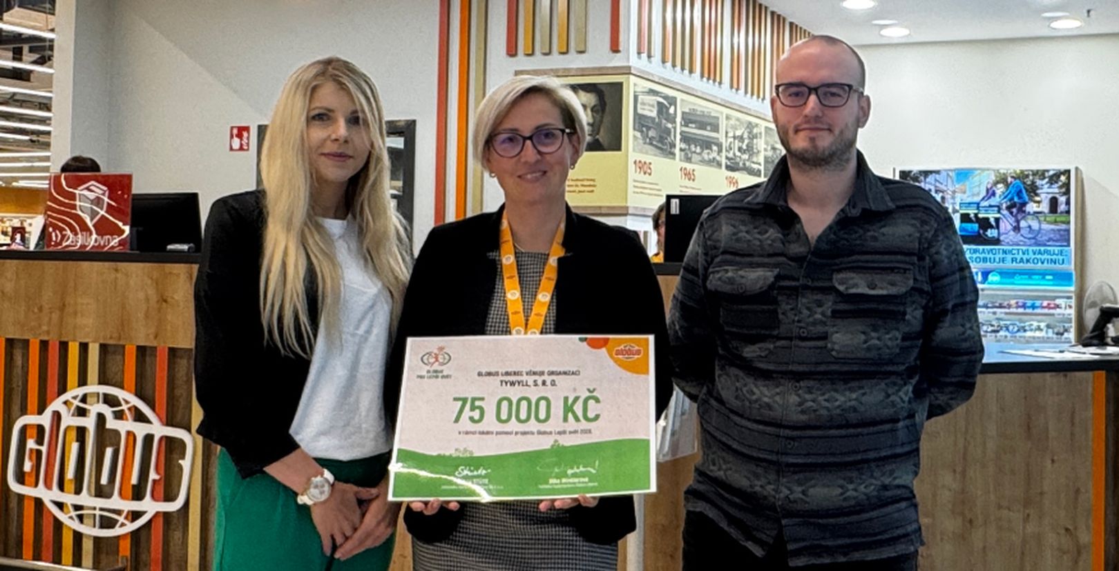 3 lidé v hypermarketu Globus s darovacím šekem na částku  75 000 Kč