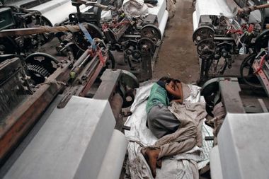 Een migratie-arbeider slaapt tussen de machines waaraan hij werkt