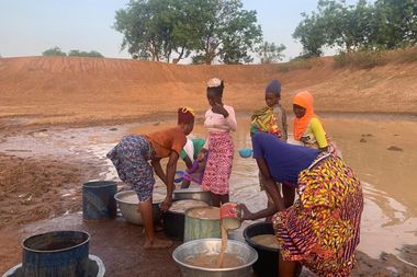 Afrikaanse vrouwen scheppen ongezuiverd water uit een grote plas water wat ooit een meer geweest moet zijn