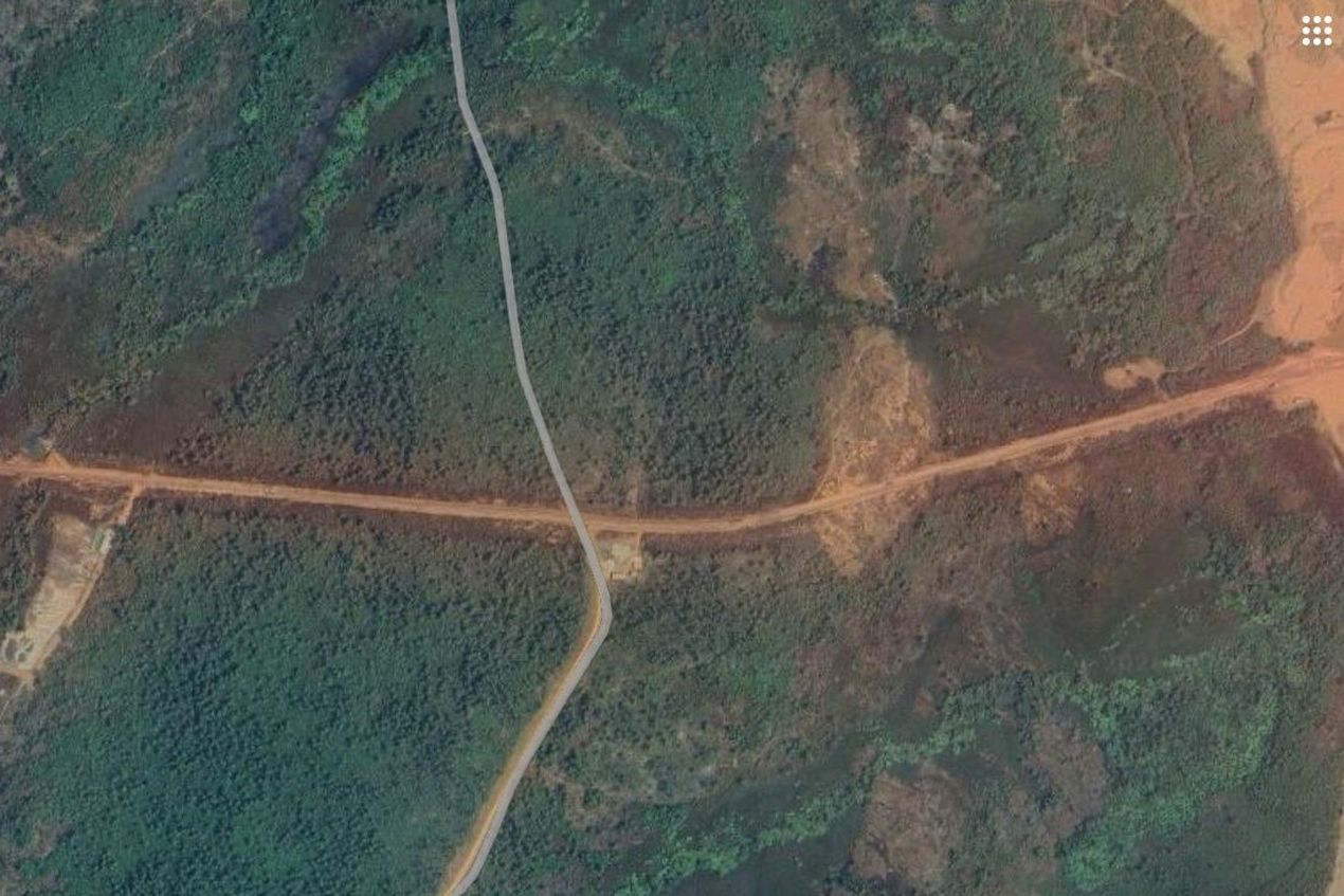 Satellietbeeld met vegetatie doorsneden door de brede corridor voor vrachtwagens naar Soumbouyadi. De stofwolk rond die corridor is duidelijk te zien.