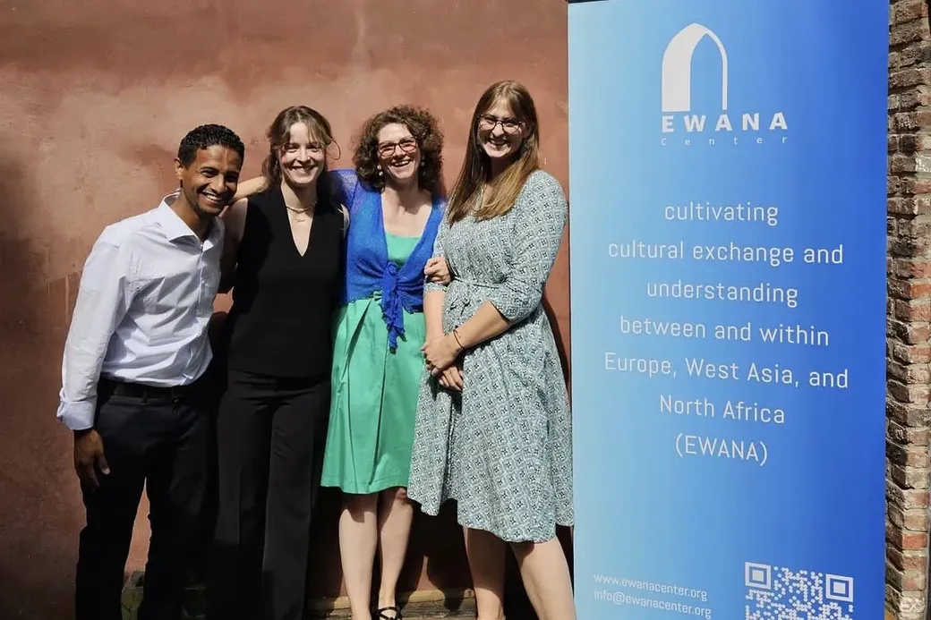 mleden van het Ewanateam poseren voor de camera naast een pancarte van de organisatie