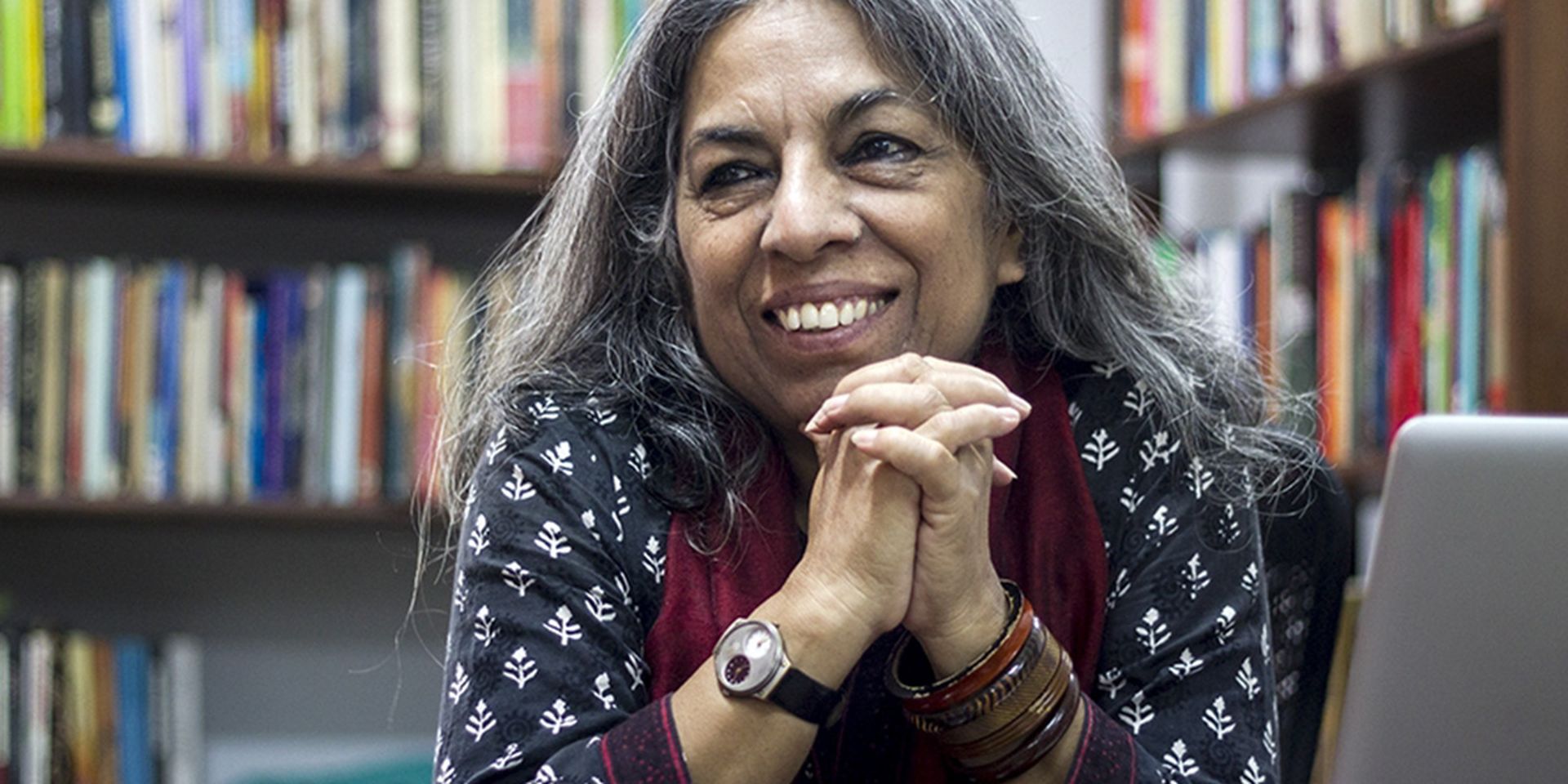 Portretbeeld van uitgeefster Urvashi Butalia voor een boekenkast