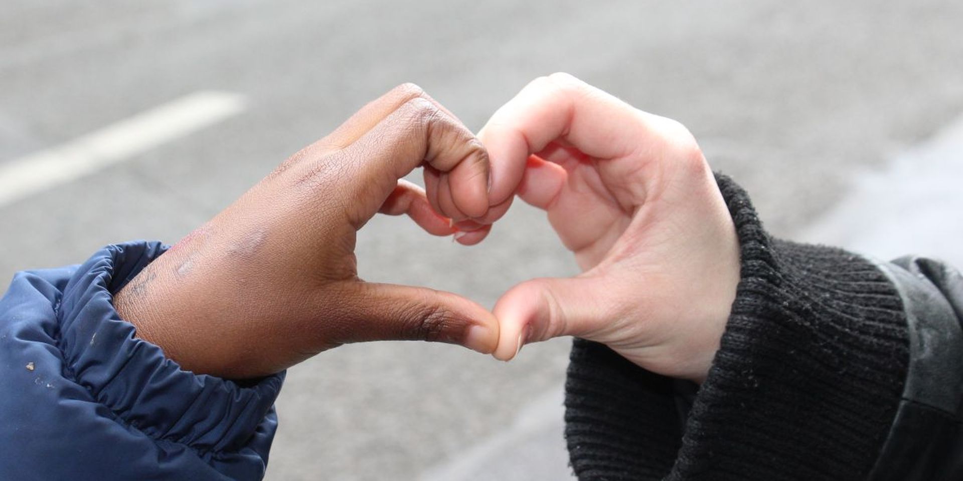 Een kinderhand en een hand van een jonge vrijwilliger vormen samen een hartje.
