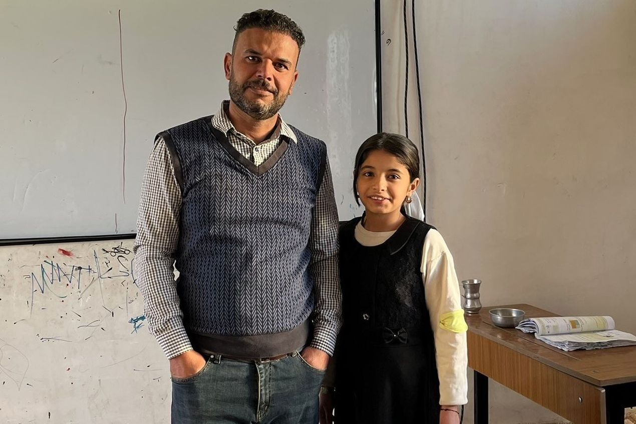 De Iraakse leraar Mohammed Khidher poseert met zijn dochter voor een schoolbord.