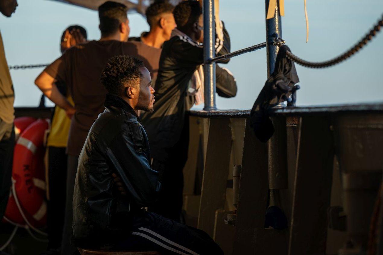 Een man aan boord van het reddingsschip Humanity 1 zit en staart over de reling naar zee.