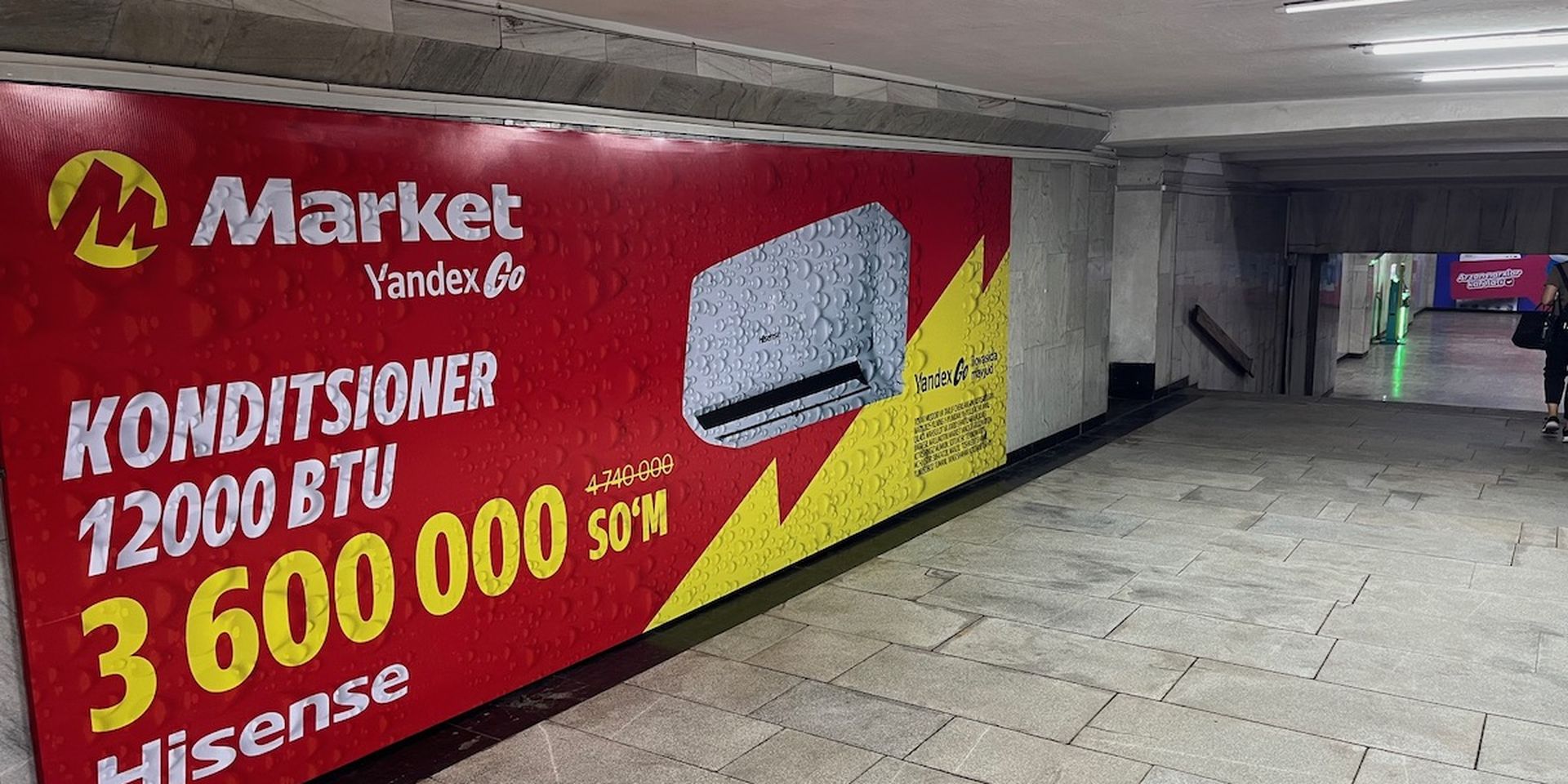 Advertisement for 12,000 BTU Hisense air conditioner priced at 3,600,000 So'm, displayed in an underground passage.