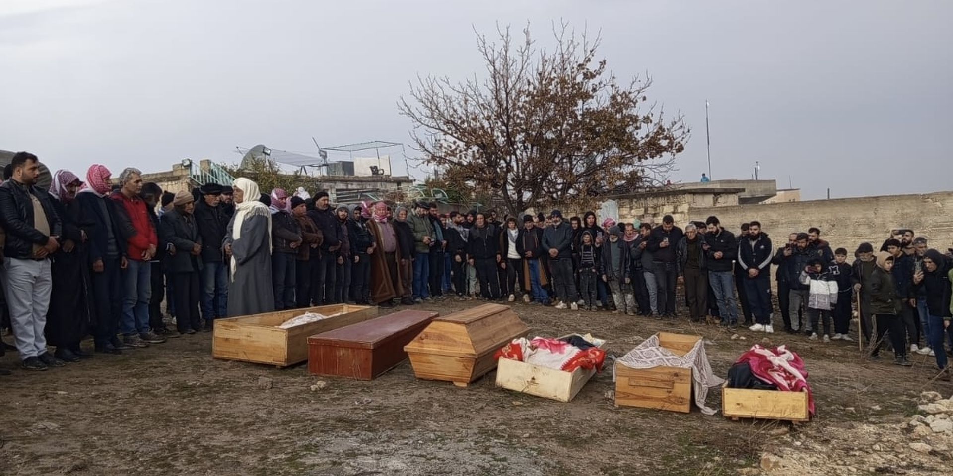 Zeven doodskisten op een veld in een dorp