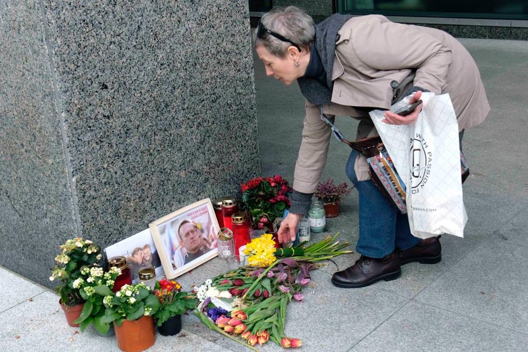 een vrouw legt bloemen neer bij een foto