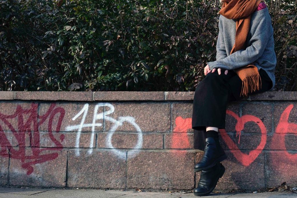 een onherkenbare vrouw zit op een muurtje