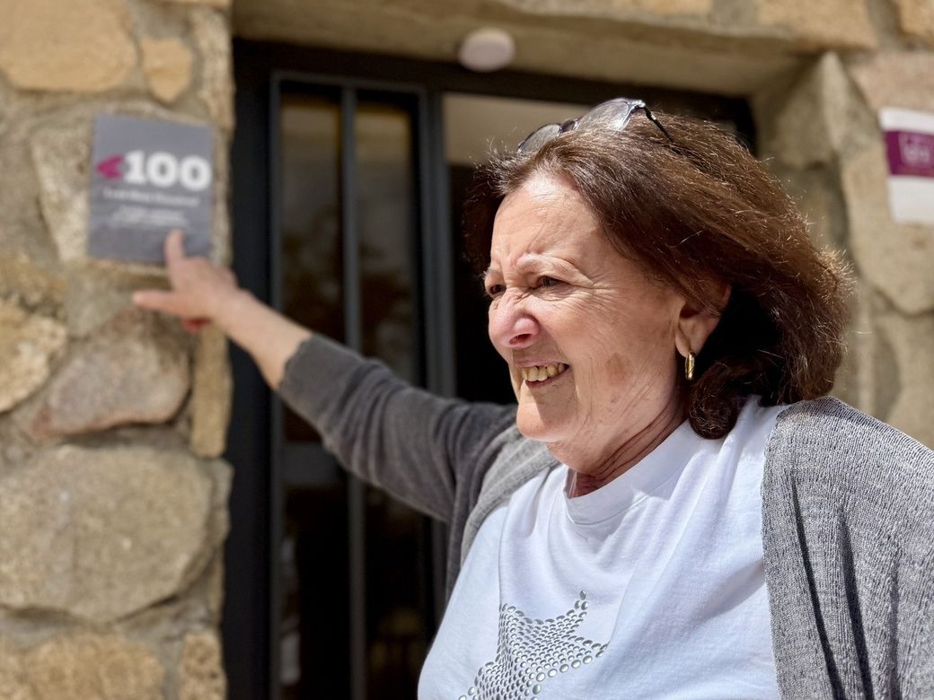 een vrouw wijst naar een bordje met het cijfer 100