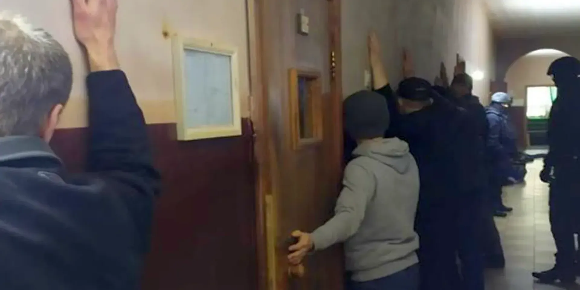 Arrestanten van de Oekraïense veiligheidsdiensten staan met de armen gespreid tegen een muur