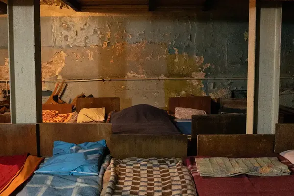 Gammele bedden met verschillende kleurrijke dekens in een ondergrondse schuilplaats