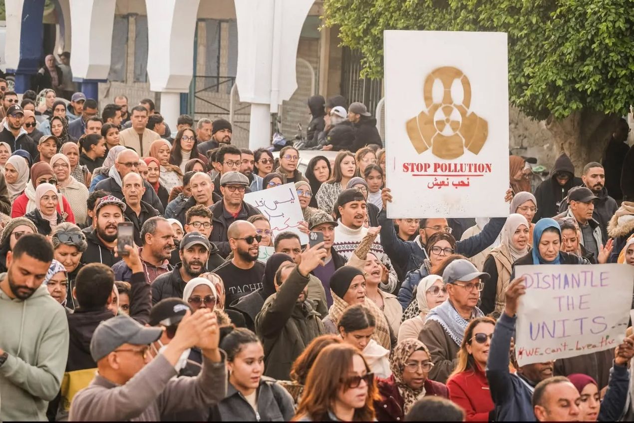 Een massa lokale bewoners in Gabès, Tunesië, is verzameld op straat en houdt borden met slogans als 'Stop Pollution' in de lucht.