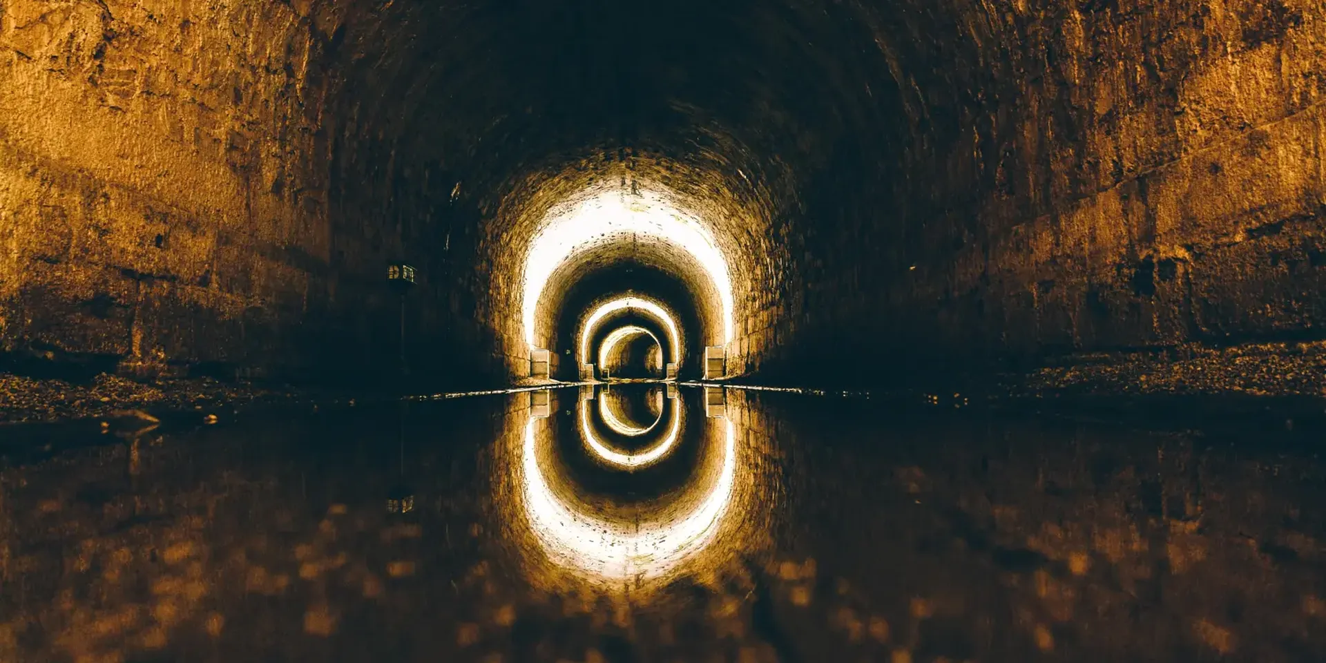 een oude ondergrondse stadsriolering. Plafondverlichting wordt weerspiegeld in het rioleringswater