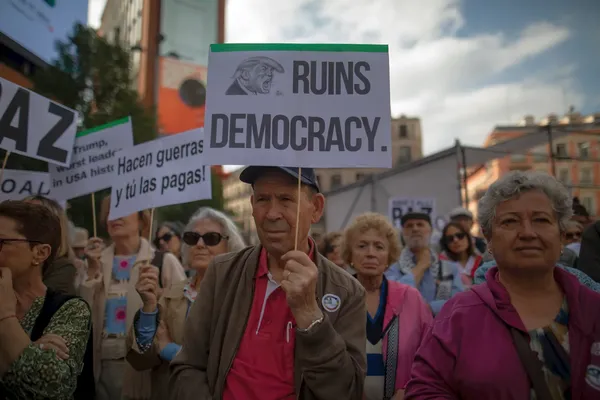 Betoging van Spanjaarden met pancartes die de Amerikaanse president Trump ervan beschuldigen de democratie te ruïneren