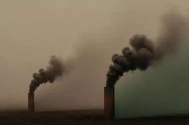 beeld van 2 schouwen die donkere rook uitspuwen