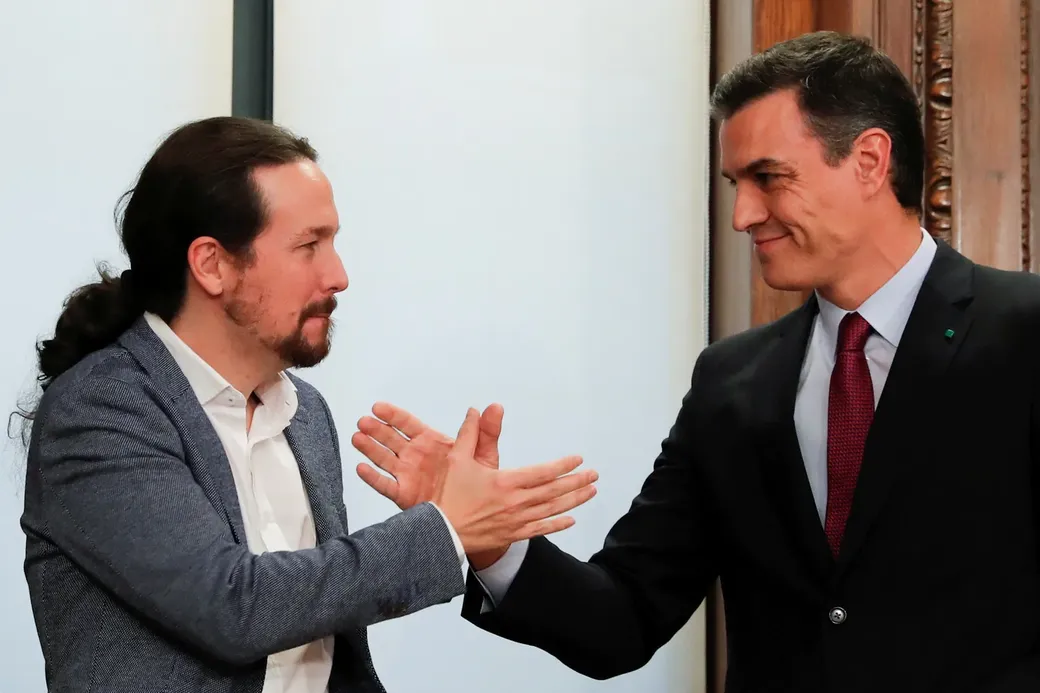 Pedro Sánchez en Unidas Podemos-leider Pablo Iglesias schudden elkaar de hand tijdens de presentatie van hun coalitieakkoord in het Spaanse parlement in Madrid op 30 december 2019
