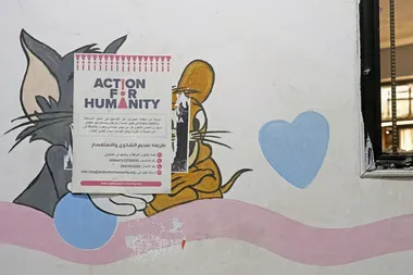 Muurschildering van Tom & Jerry overplakt met een affiche van Action for Humanity