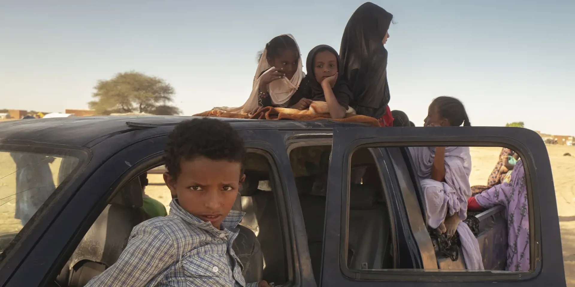 Malinese kinderen zitten in de laadbak van een auto aan een Mauritaanse grenspost.