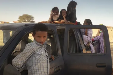 Malinese kinderen zitten in de laadbak van een auto aan een Mauritaanse grenspost.