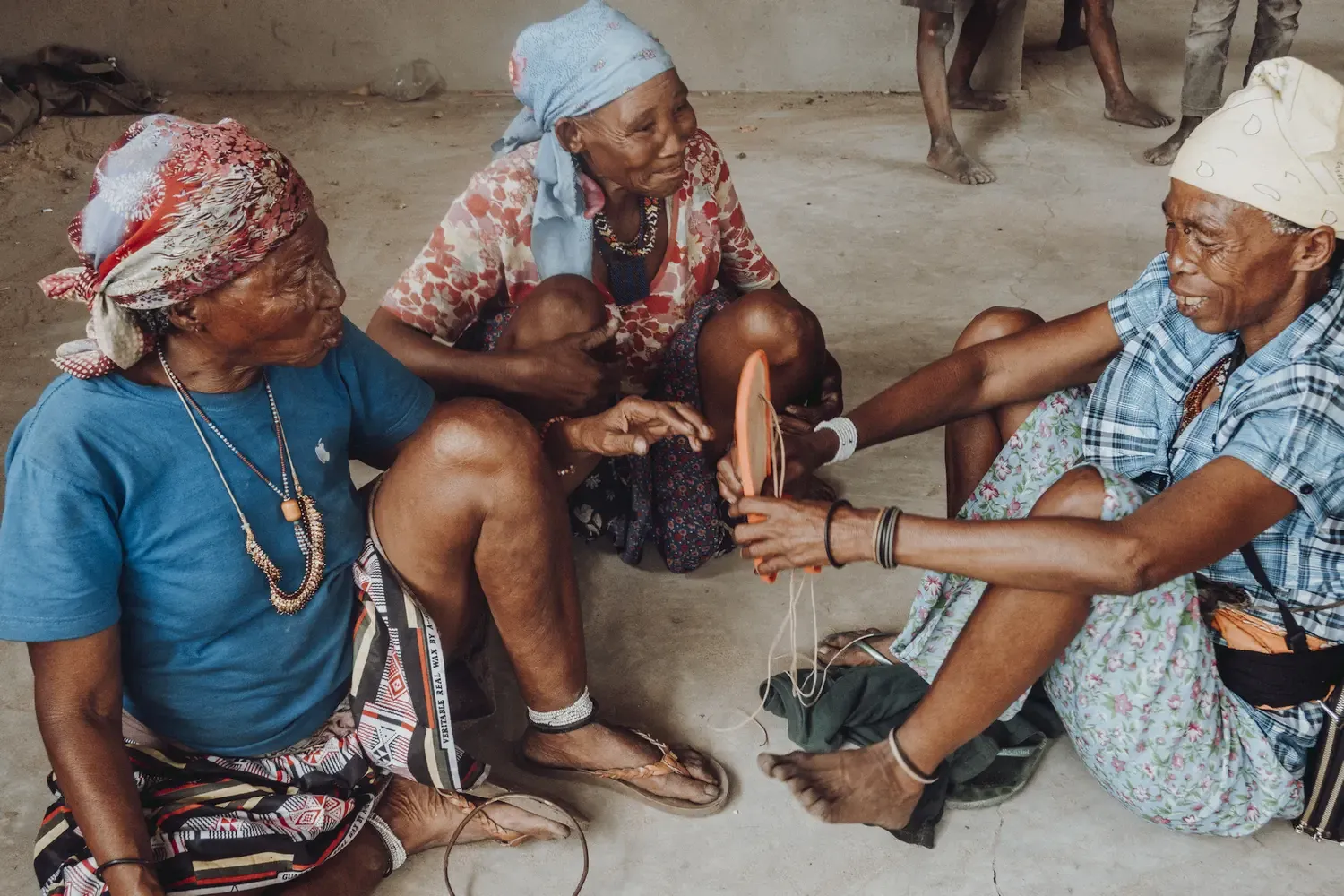 Drie San-zussen in Nhoma, Namibië, passen een 3D-geprint prototype van een traditionele sandaal die ontworpen werd voor de jacht.
