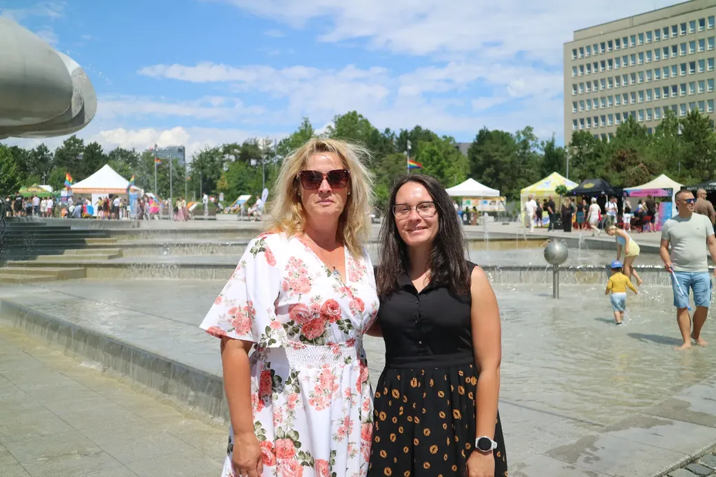 Twee vrouwen poseren voor de camera. Op de achtergrond een fontein