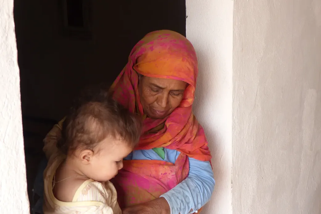 Een oudere vrouw,  Zaïma Salem, staat in een deuropening met een kind op de arm