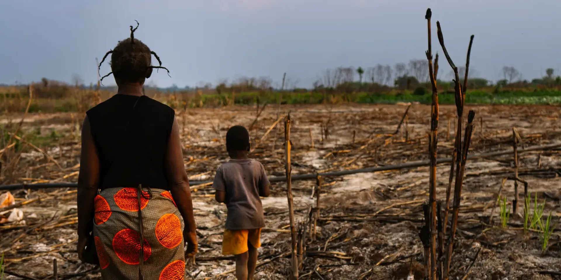 Een moeder en zoon wandelen door verdord gebied rond een mijn