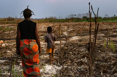 Een moeder en zoon wandelen door verdord gebied rond een mijn