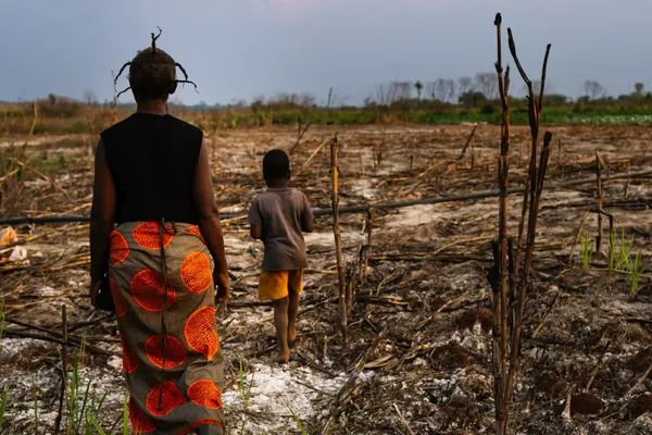 Een moeder en zoon wandelen door verdord gebied rond een mijn