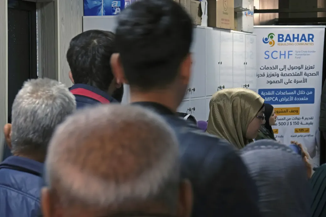 Mensen staan in een rij aan een hulppunt van de Syrische ngo Bahar