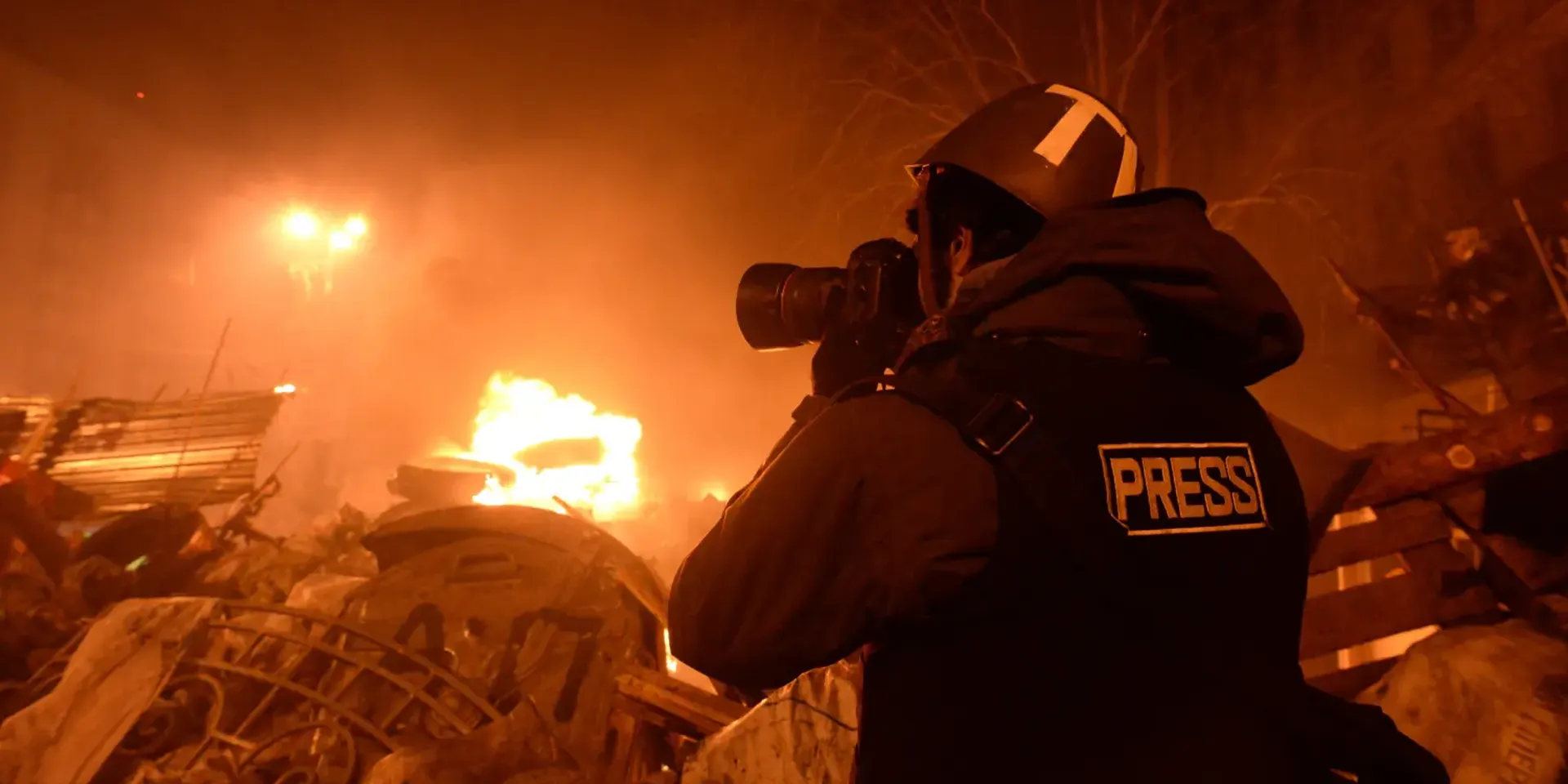 beeld van een journalist die een foto neemt van een vernielde omgeving.