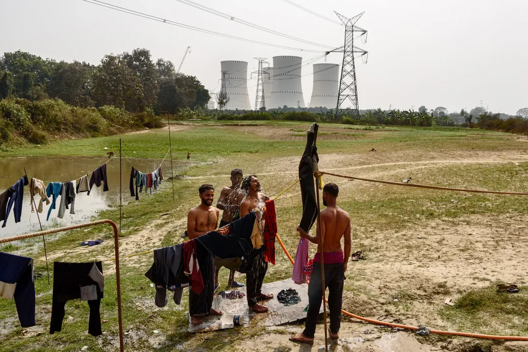 Enkele lokale boeren wassen zich onder de pylonen in een veld. Als er nucleair afval in de rivier zou lekken, is dat een ramp voor de akkers, zeggen ze.