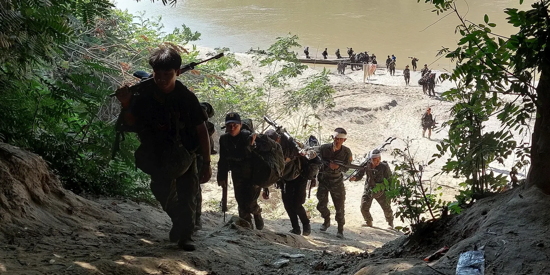 Soldaten beklimmen de steile oever van een rivier