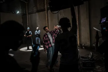 Een cameraploeg filmt een rapper in een grote afgesloten ruimte tijdens opnames voor een videoclip