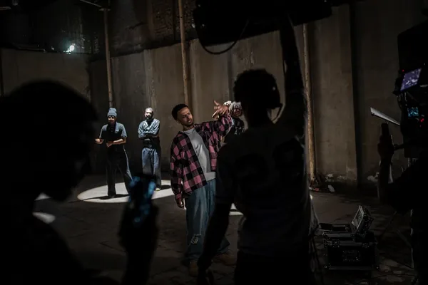 Een cameraploeg filmt een rapper in een grote afgesloten ruimte tijdens opnames voor een videoclip