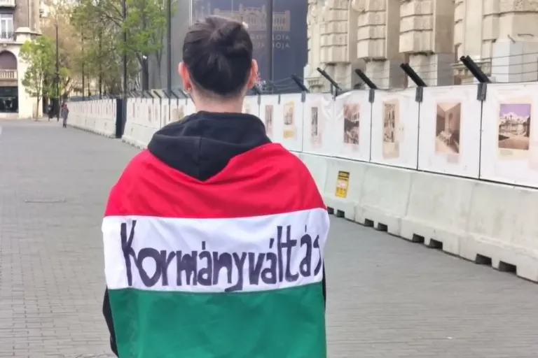 Achteraanzicht van een man met de Hongaarse vlag gedrappeerd rond zijn schouders