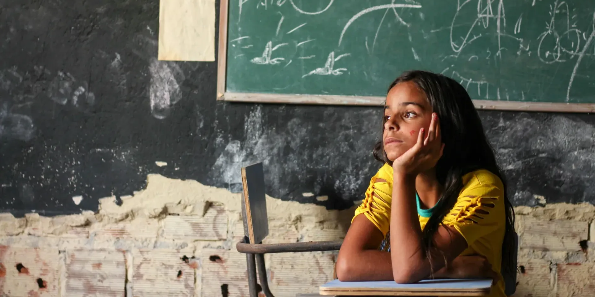 een meisje op een schoolbank kijkt dromerig uit het raam