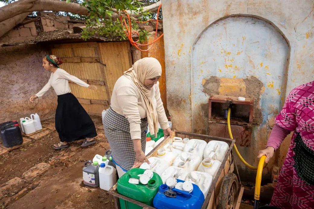 vrouwen collecteren water aan een openbare kraan