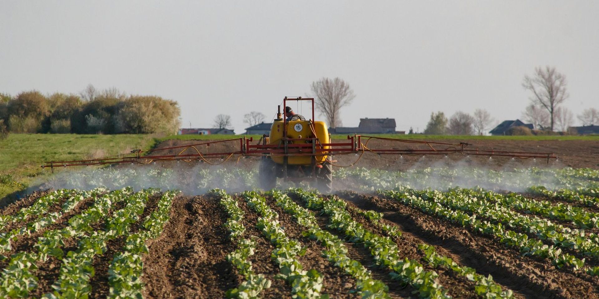 een tractor verspreid pesticiden over een veld