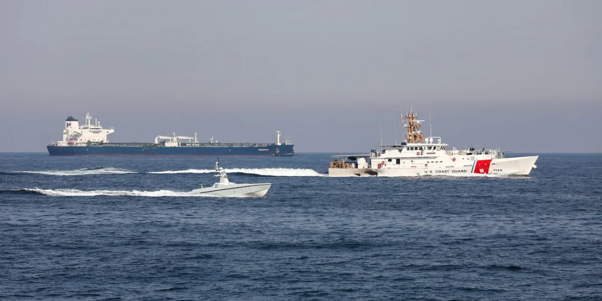Een schip van de Amerikaanse Kustwacht en een onbemand vaartuig varen door de Straat van Hormuz. Op de achtergrond een olietanker. (foto uit 2023)