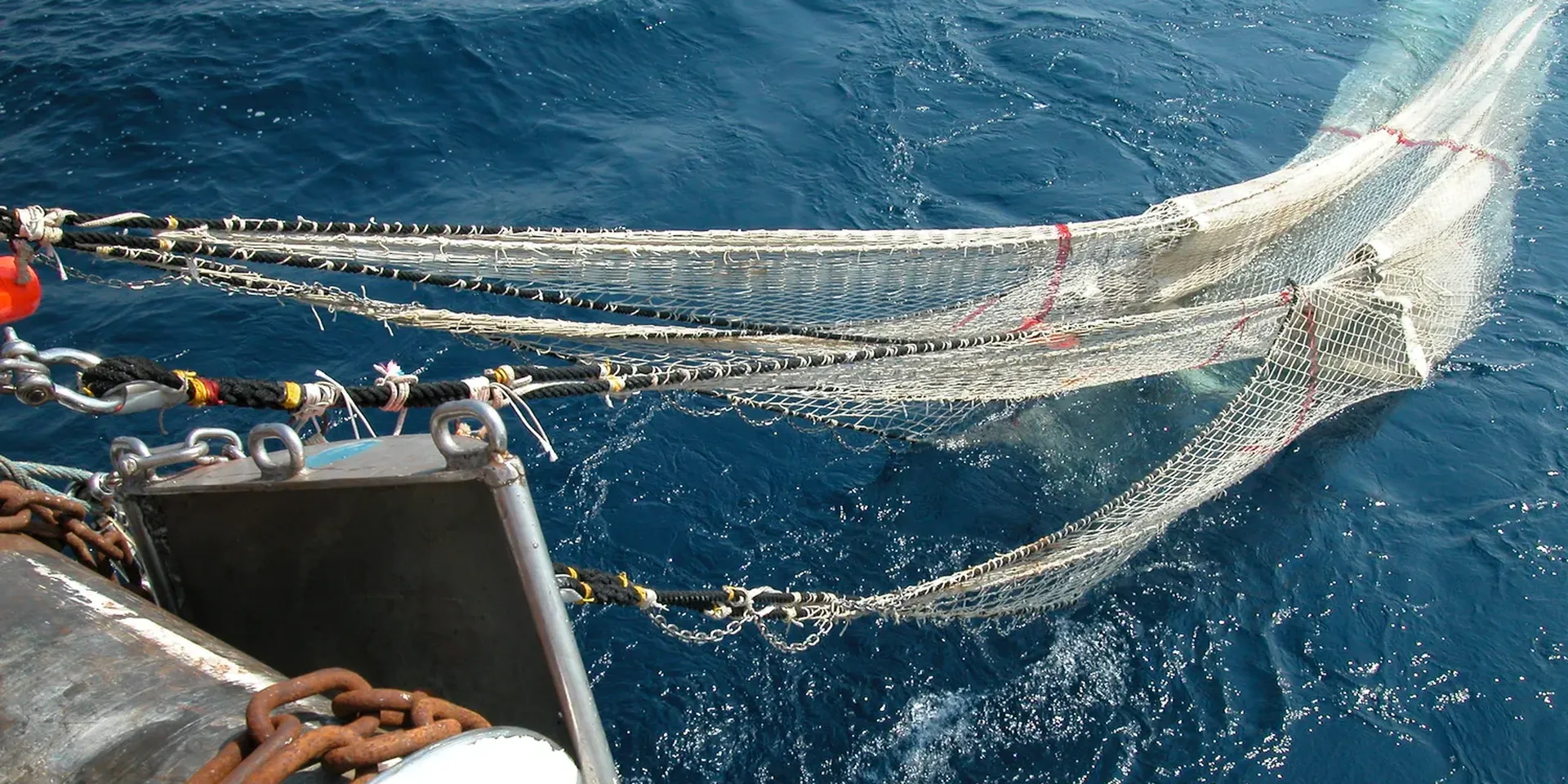 Een sleepnet wordt aan boord van een vissersboot getrokken