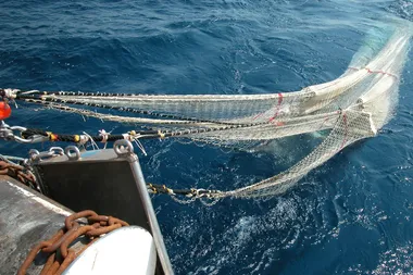 Een sleepnet wordt aan boord van een vissersboot getrokken