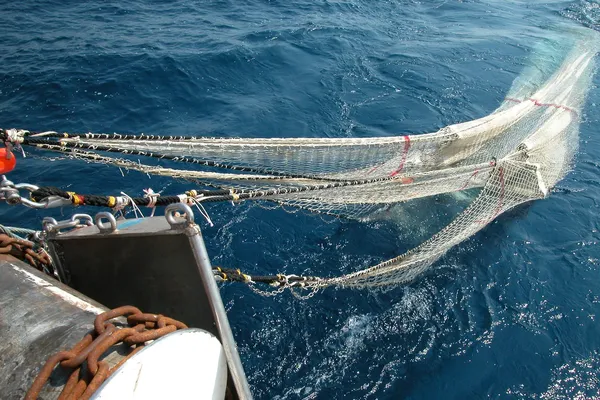Een sleepnet wordt aan boord van een vissersboot getrokken