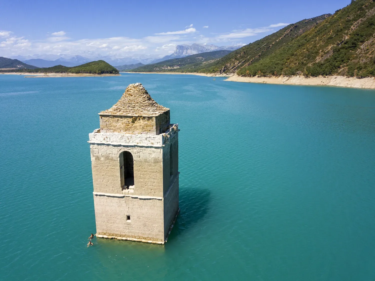 Een kerktoren staat eenzaam in het midden van een groot stuwmeer