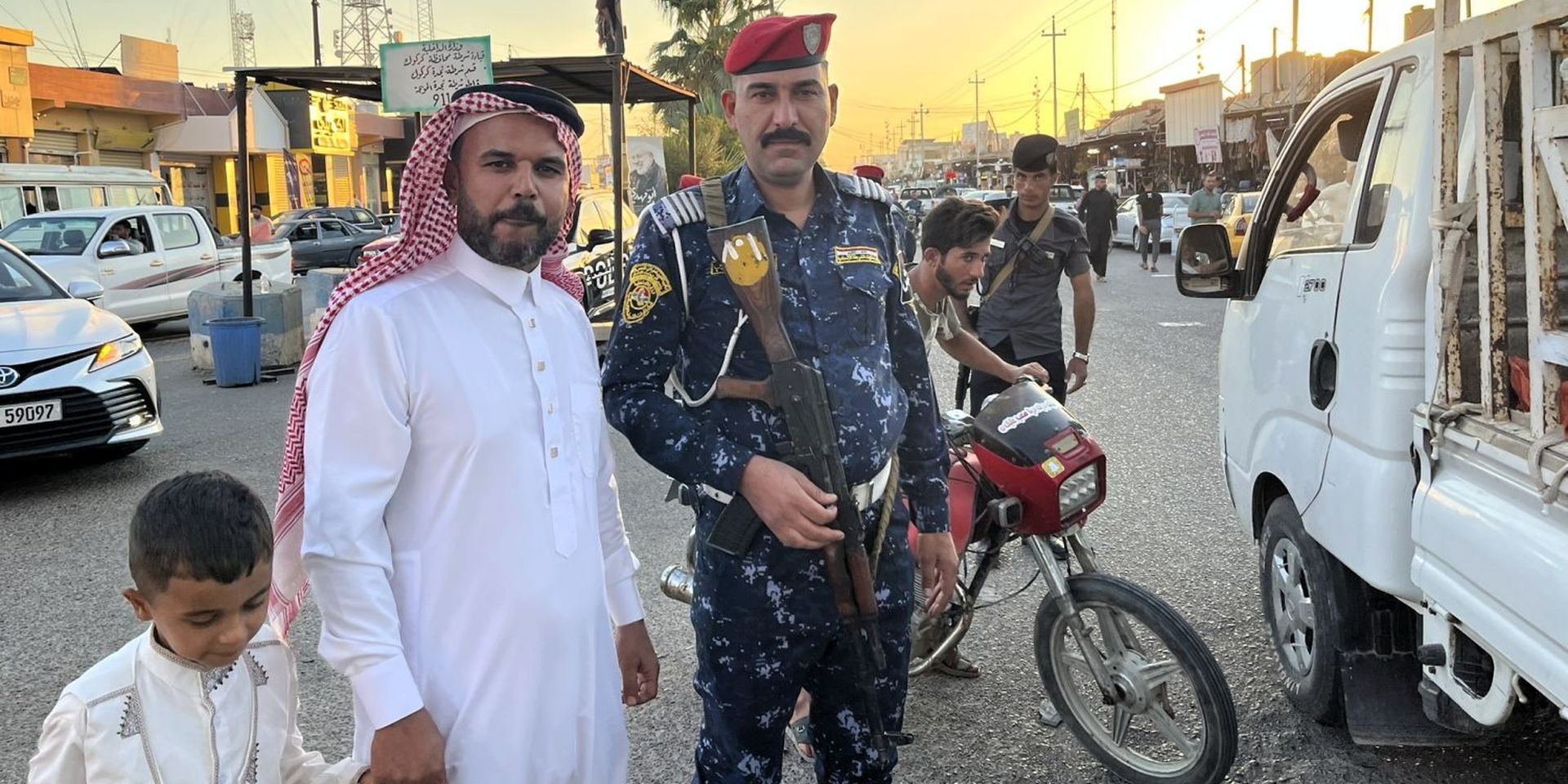 Een Iraakse jongen, man en politieagent poseren op straat in de stad Hawija.