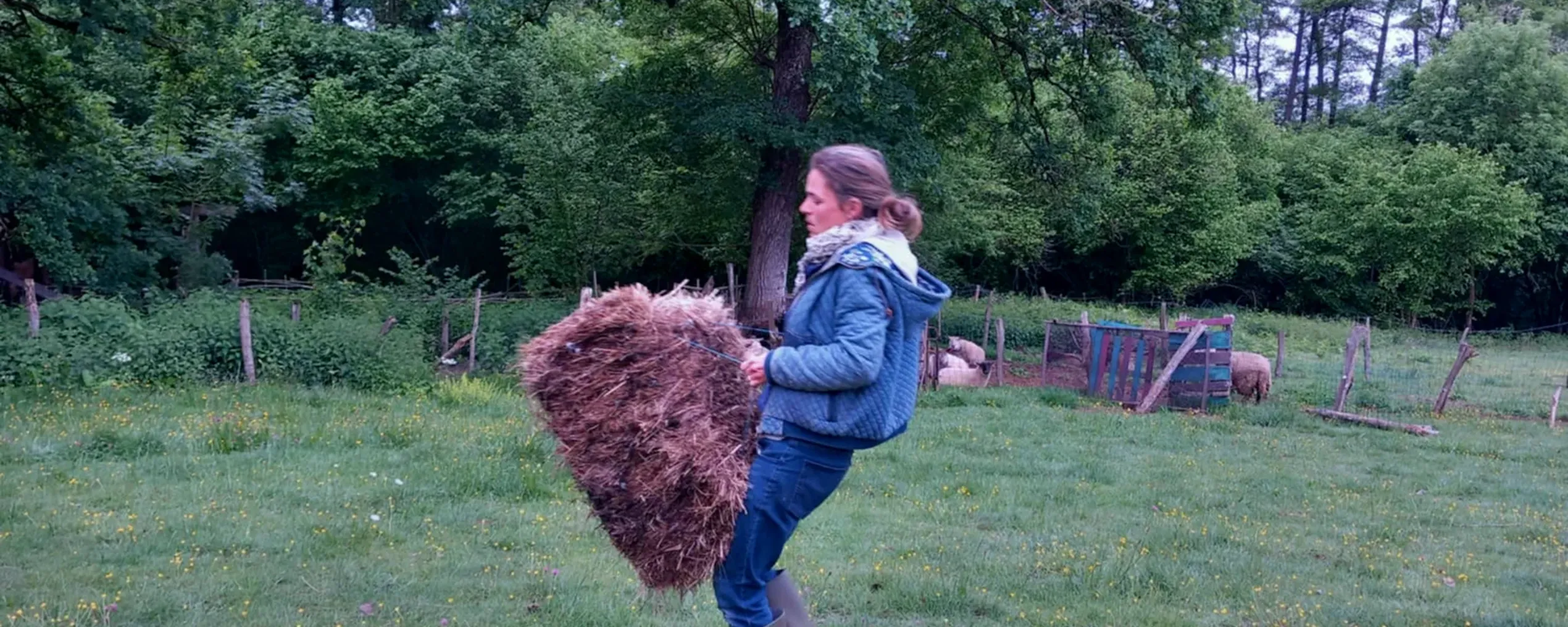 jonge vrouw draagt hooibaal in wei