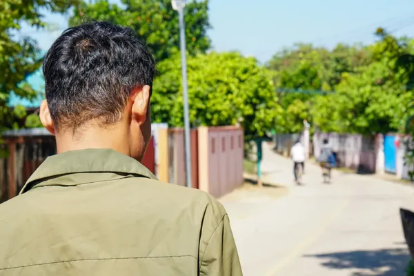 Een Birmese ex-scammer staat met zijn rug naar de camera