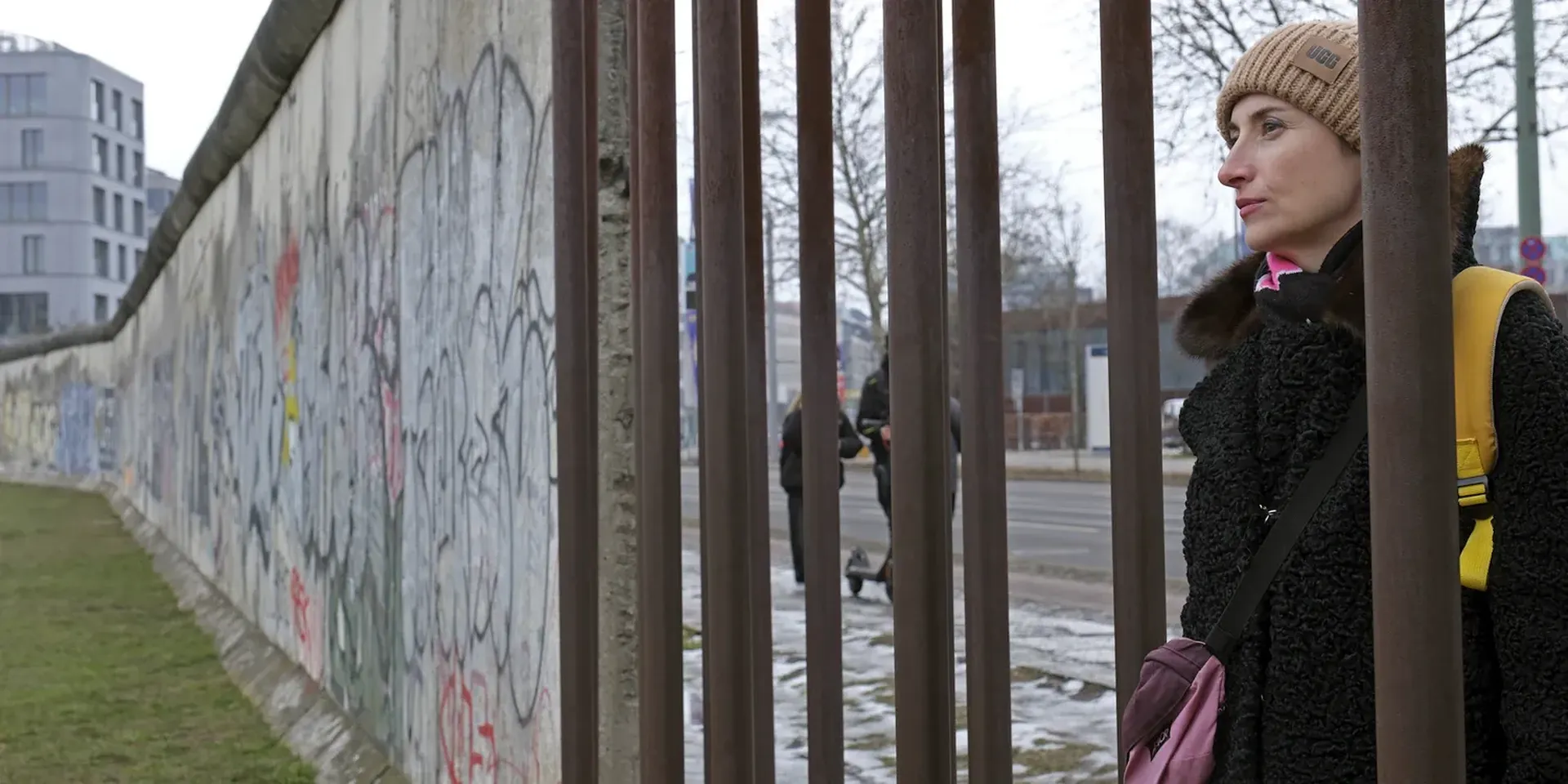 Viktoria Lomasko kijkt door een hek aan de voormalige Berlijnse muur